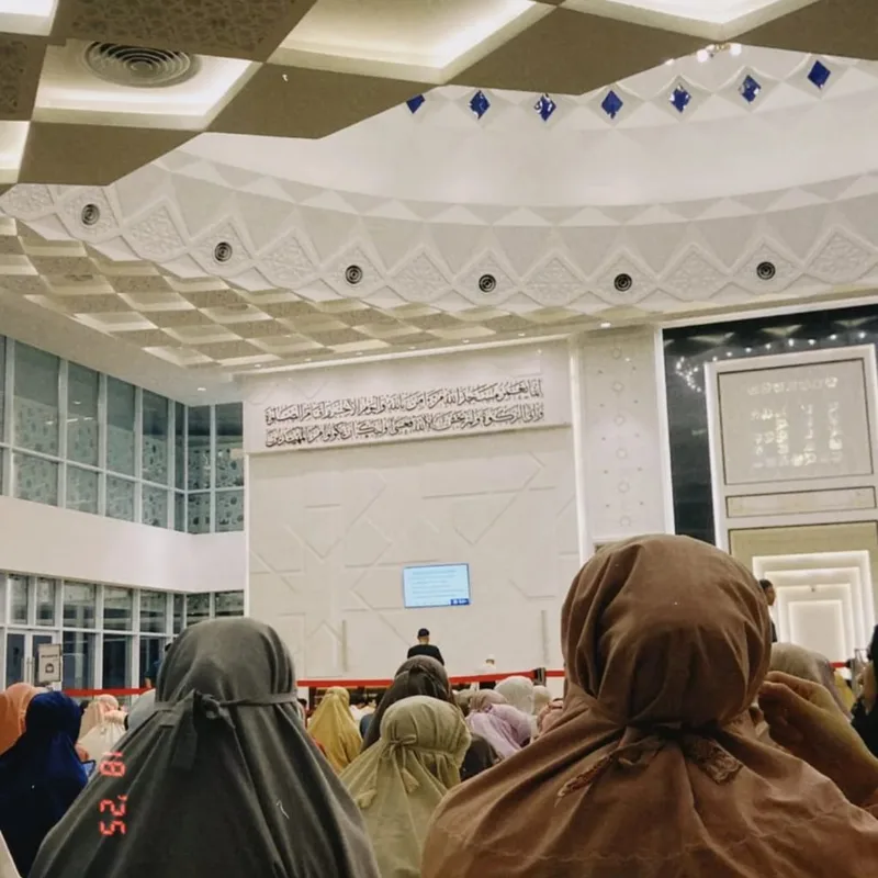 Women worshippers in prayer garments facing the front of a mosque hall